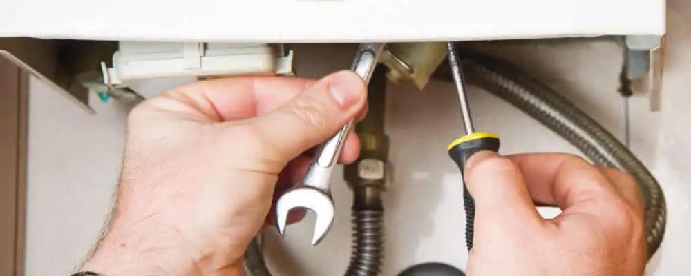 Boiler repair technician tightening pipe fittings and connections in Escondido, CA