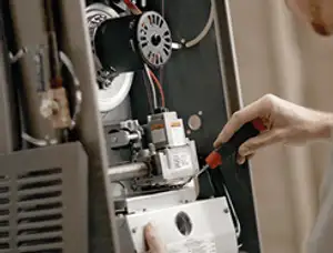 Furnace repair technician inspecting internal components and wiring in Escondido, CA