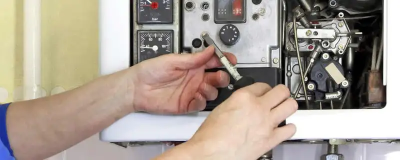 Heating repair technician adjusting boiler controls and components in Escondido, CA