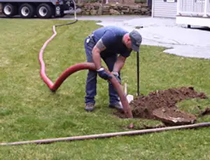 Septic pumping technician servicing a residential septic tank with a vacuum hose in Escondido, CA