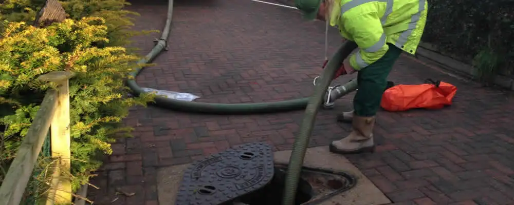 Septic tank cleaning technician servicing a septic tank with a vacuum hose in Escondido, CA