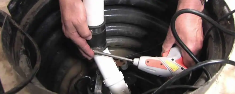 Sump pump installation technician connecting PVC discharge piping in Escondido, CA