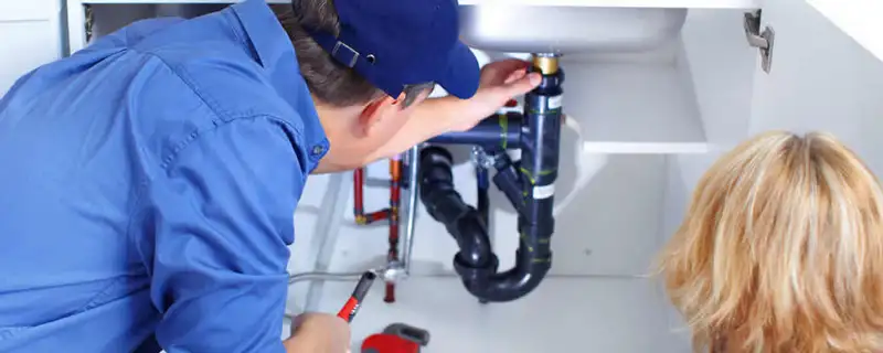 Plumber repairing under-sink drain pipes and fittings in Escondido, CA