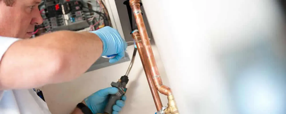 Water heater repair technician testing copper pipe connections and controls in Escondido, CA